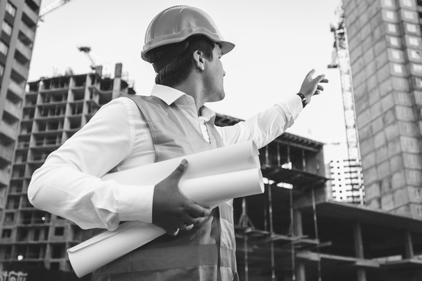 engineer with blueprints checking building site construction - Fotó, kép