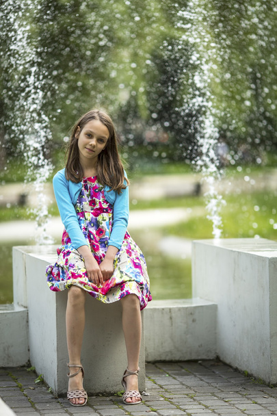 petite fille assise près de la fontaine
 - Photo, image