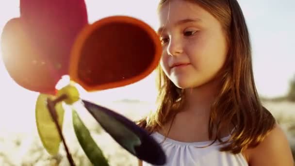 κορίτσι που παίζουν σε εξωτερικούς χώρους με ανεμόμυλο πολύχρωμο παιχνίδι - Πλάνα, βίντεο