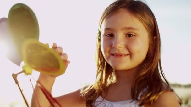дівчина на відкритому повітрі грає з барвистою іграшкою вітряної млини
 - Кадри, відео