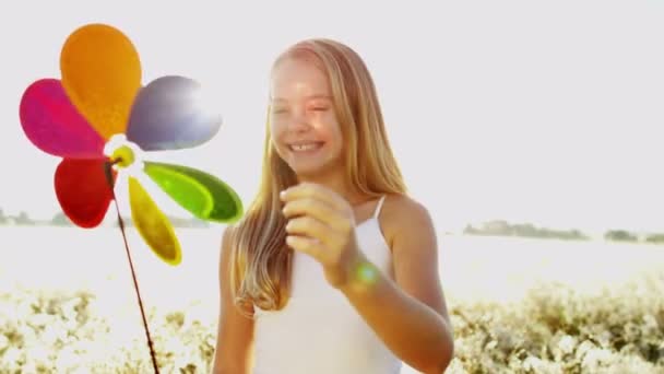 κορίτσι που παίζουν σε εξωτερικούς χώρους με ανεμόμυλο πολύχρωμο παιχνίδι - Πλάνα, βίντεο
