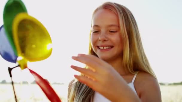 Mädchen im Freien spielt mit buntem Windrad-Spielzeug - Filmmaterial, Video