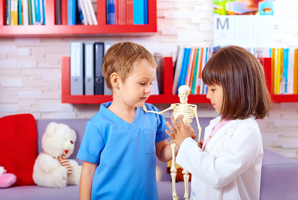 cute kids playing in doctors with toy human skeleton - Фото, зображення