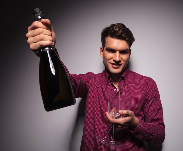 Casual young man presenting a bottle of wine - 写真・画像