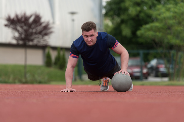Young Man Exercising Push-Ups On Medicine Ball Outdoor - 写真・画像