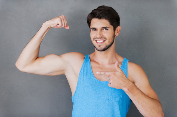 Cheerful muscular man pointing his bicep - Φωτογραφία, εικόνα