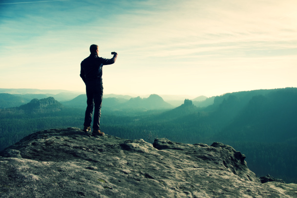 Uzun boylu uzun yürüyüşe çıkan kimse fotoğraf dağ tepe üzerinde akıllı telefonla güneş doğarken alıyor. - Fotoğraf, Görsel