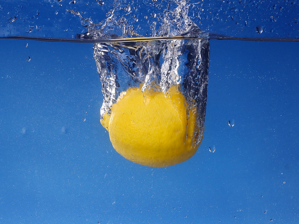 Целый лимон упал в воду на градиентный синий фон
 - Фото, изображение
