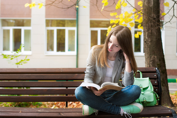 Student reading book on bench - Foto, imagen