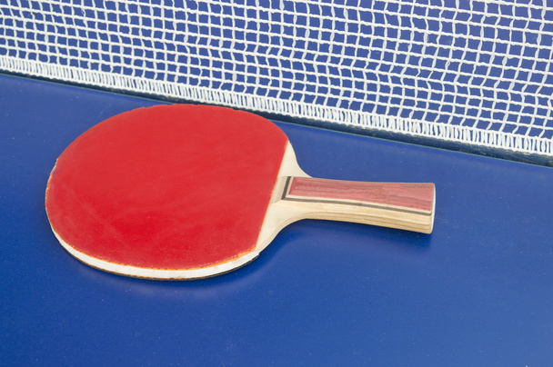 Table tennis paddle and net on a table - Fotó, kép