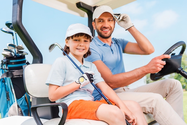 man and his little son sitting in golf cart - 写真・画像