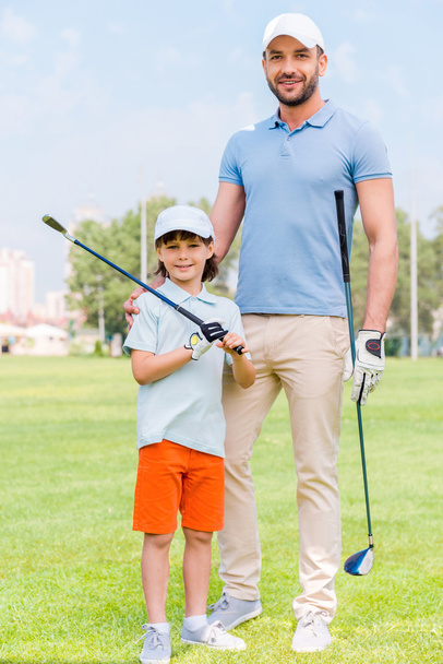 man embracing his son on golf course - Фото, зображення