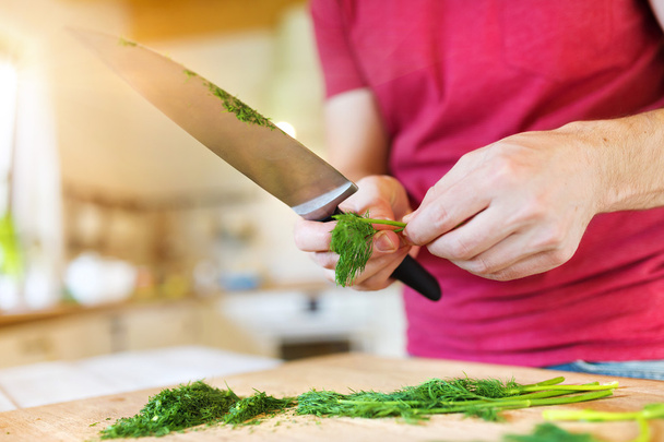 Man in the kitchen cutting dill - Foto, imagen