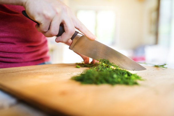 Man in the kitchen cutting dill - Фото, изображение