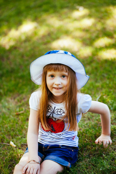 Portrait of a cute girl in a park on a meadow - Fotó, kép
