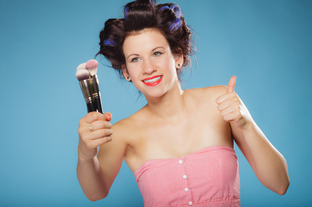 mujer en rodillos de pelo sostiene cepillos de maquillaje - Foto, imagen