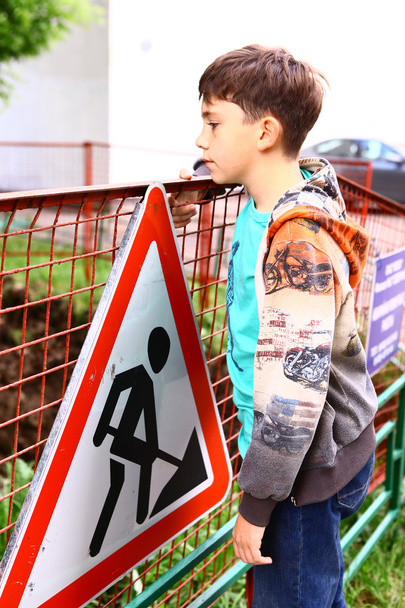 preteen handsome boy at the construction border with warning sig - Photo, Image