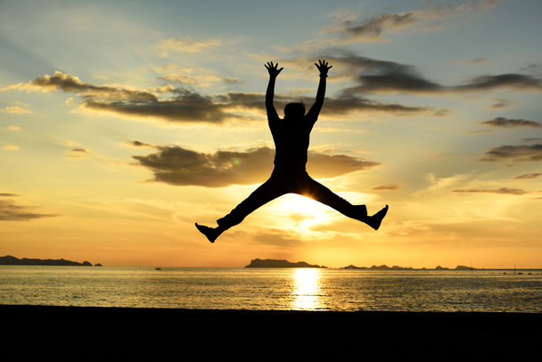 Siluetti hyppäävä mies rannalla
 - Valokuva, kuva