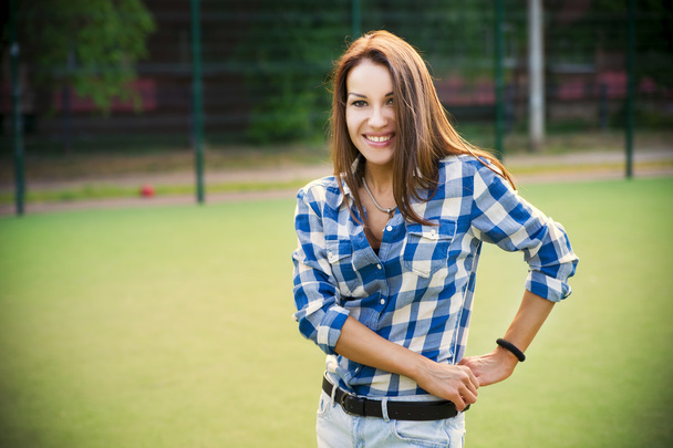 Beautiful young woman with fitness tracker on the football field - Photo, Image