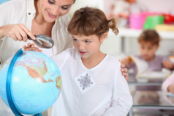 Schoolmistress teaching geography with globe - Foto, Imagen