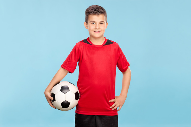 Little boy in a red jersey holding a football  - Foto, imagen