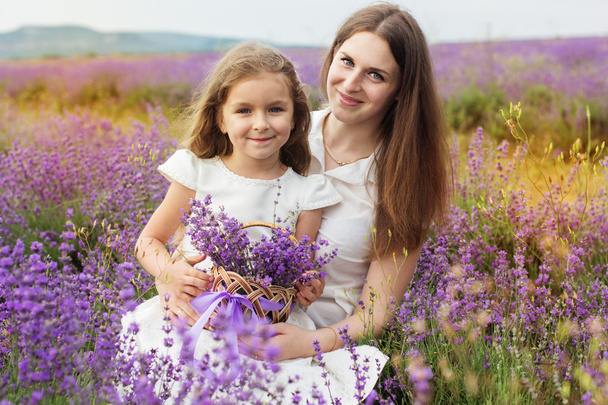 Kind meisje met moeder op lavendel gebied zijn holding mand - Foto, afbeelding