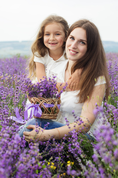 Mother with daughter in lavender field are holding basket - Foto, imagen