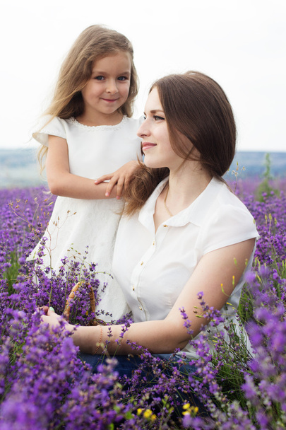 Mother with daughter in lavender field are holding basket - Fotoğraf, Görsel