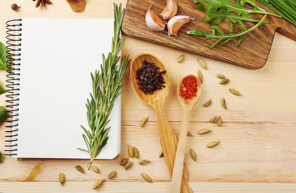 Open recipe book with fresh herbs and spices on wooden background - Фото, зображення