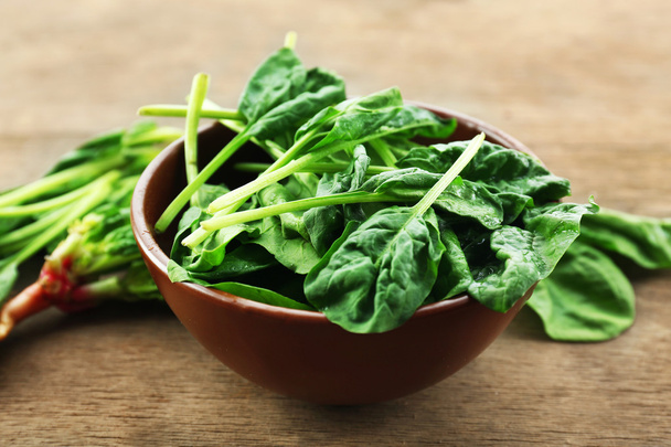 Bowl of fresh spinach leaves on wooden table, closeup - Fotoğraf, Görsel