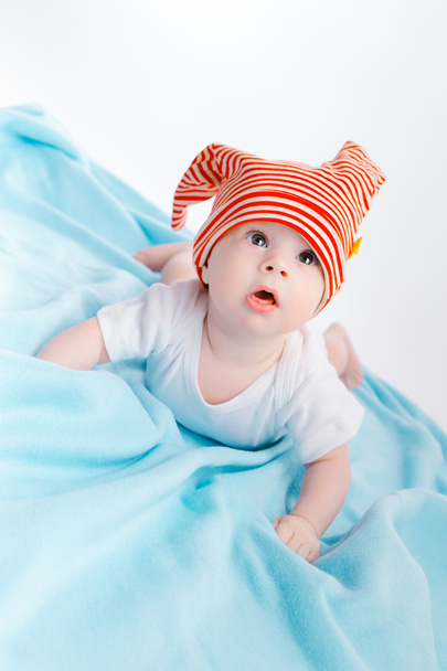 toddler in a striped hat on a blue blanket - Fotoğraf, Görsel