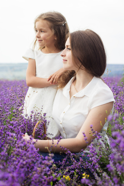Mother with daughter in lavender field are holding basket - Fotó, kép