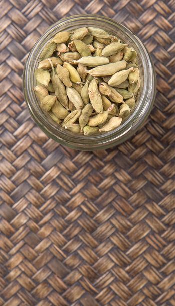 Cardamom spices in a mason jar over wicker background - Photo, Image