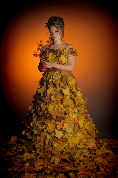 The woman in a dress from autumn leaves - 写真・画像