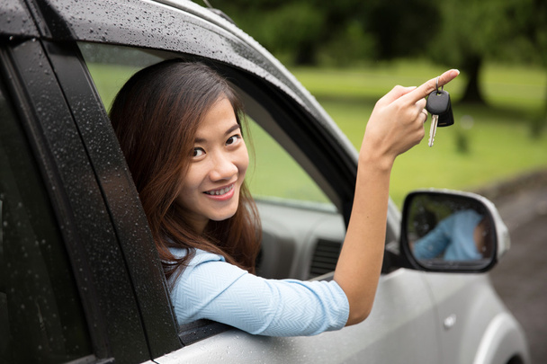 Young asian woman inside a car, hold the key out from the window - Foto, Bild