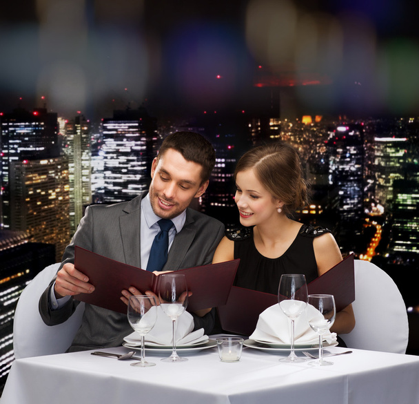 smiling couple with menus at restaurant - Fotó, kép
