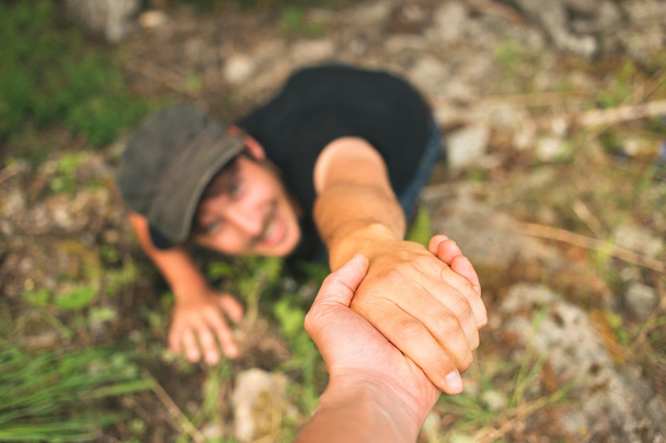 Hand helping a man to raise after falling - Φωτογραφία, εικόνα