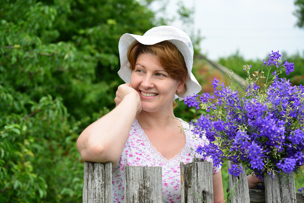 Woman with   wildflowers near  wooden fence in the village - Foto, Imagen