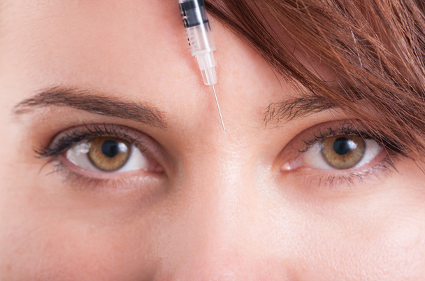 Botox syringe needle between eyes on forehead - Fotoğraf, Görsel