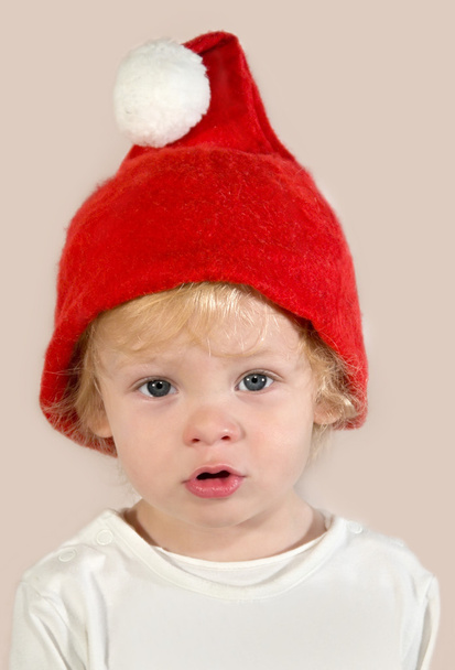 Sad kid in a red Santa Claus hat - Fotografie, Obrázek