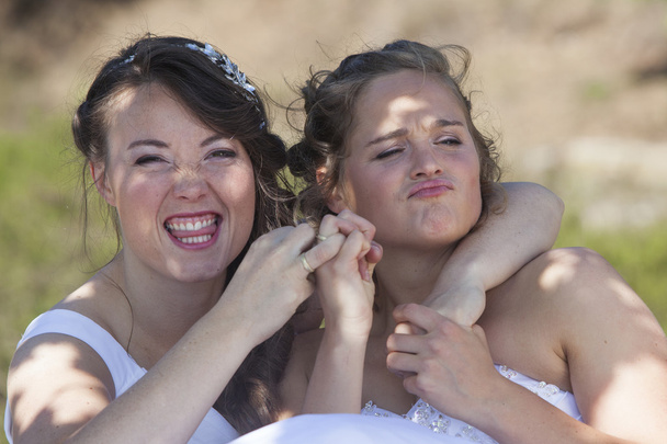 two brides smile and have fun with their wedding rings in nature - Photo, Image
