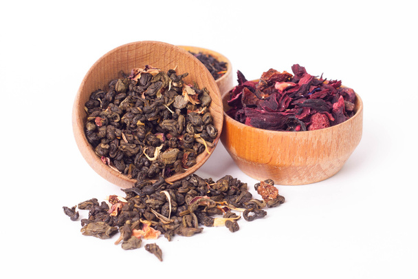 木製プレートは、白い背景の上でお茶を乾燥させます。赤、緑、黒茶の葉。マクロ写真. - 写真・画像