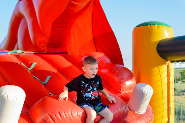Blonde boy (7-9 years) sitting in bouncy castle - Photo, Image