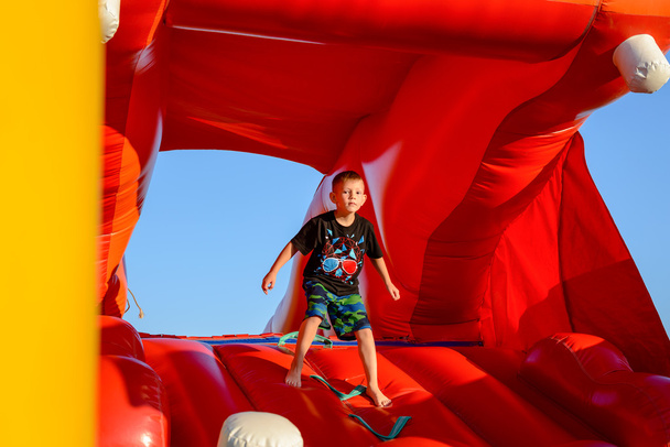 Plavovlasý chlapec v červené skákací hrad - Fotografie, Obrázek