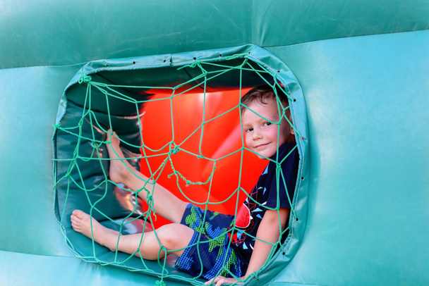 Small boy sitting in window of bouncy castle - Zdjęcie, obraz