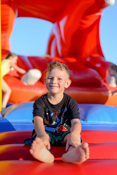 Smiling little boy sitting on a jumping castle - Photo, Image