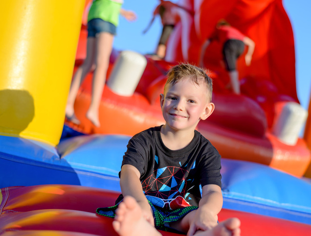 Smiling little boy sitting on a jumping castle - Photo, Image