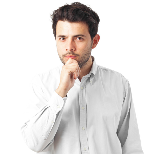 junger Mann denkt mit einer Hand am Kinn auf weißem Hintergrund - Foto, Bild