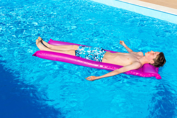 Dutch teenage boy lying  on air mattress in swimming pool - 写真・画像
