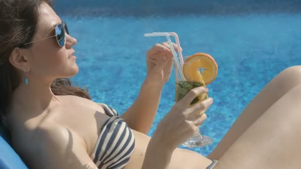 Hot chick drinking cocktail near swimming pool, smiling, teasing - Filmati, video